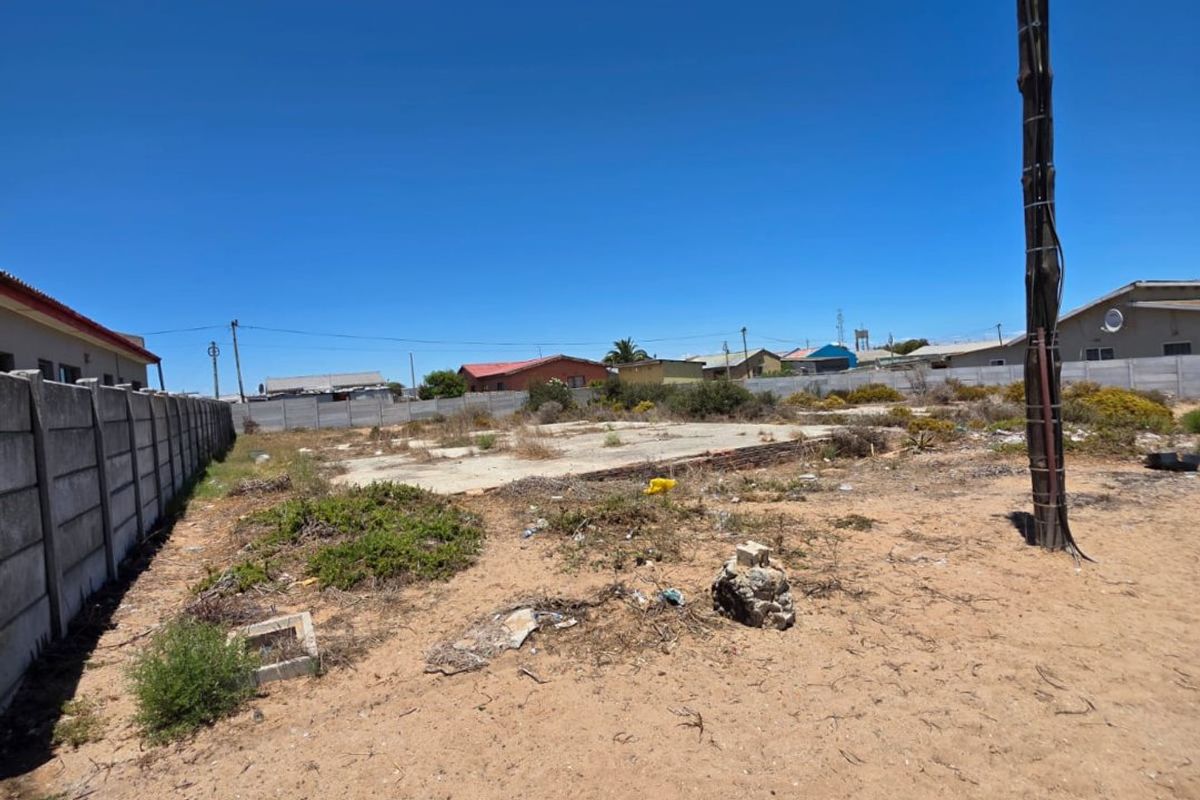 Vacant residential plot featuring a concrete slab foundation, enclosed by precast concrete boundary walls, with surrounding vegetation and utility infrastructure.