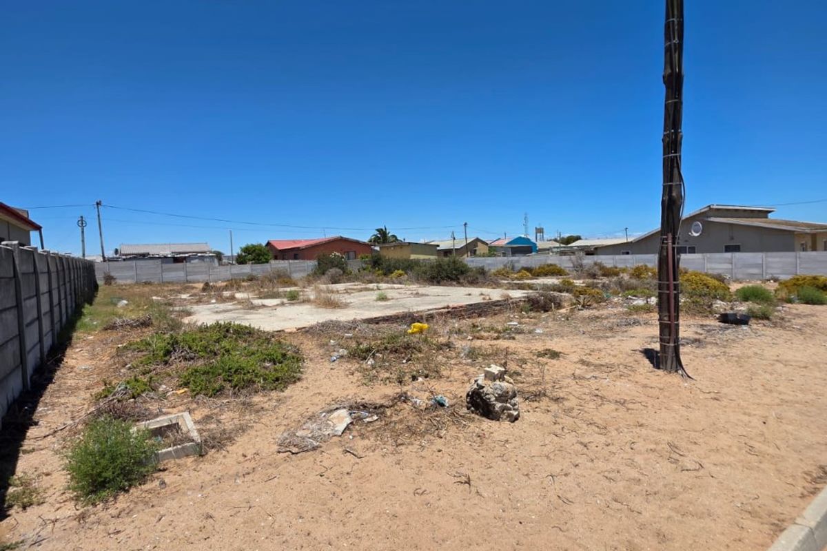 Vacant residential land featuring a concrete slab foundation, boundary wall, and utility pole, situated in a developed neighborhood.