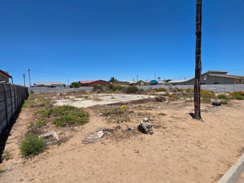 Vacant residential land featuring a concrete slab foundation, boundary wall, and utility pole, situated in a developed neighborhood.