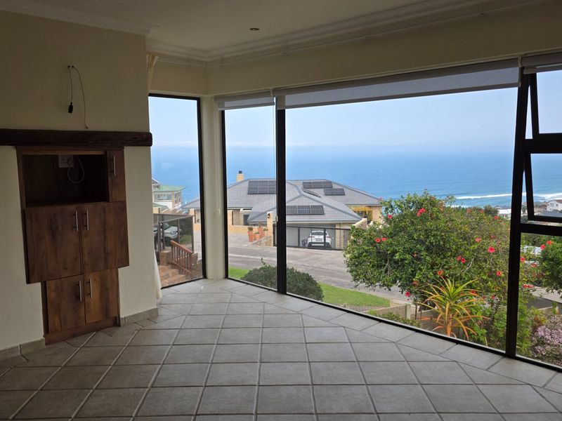 Spacious living area featuring large windows with panoramic ocean views, tiled flooring, and built-in cabinetry, offering a bright and open atmosphere.