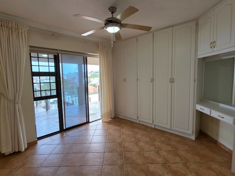 Spacious bedroom featuring built-in cupboards, a built-in vanity, ceiling fan, and sliding glass doors leading to an outdoor area.