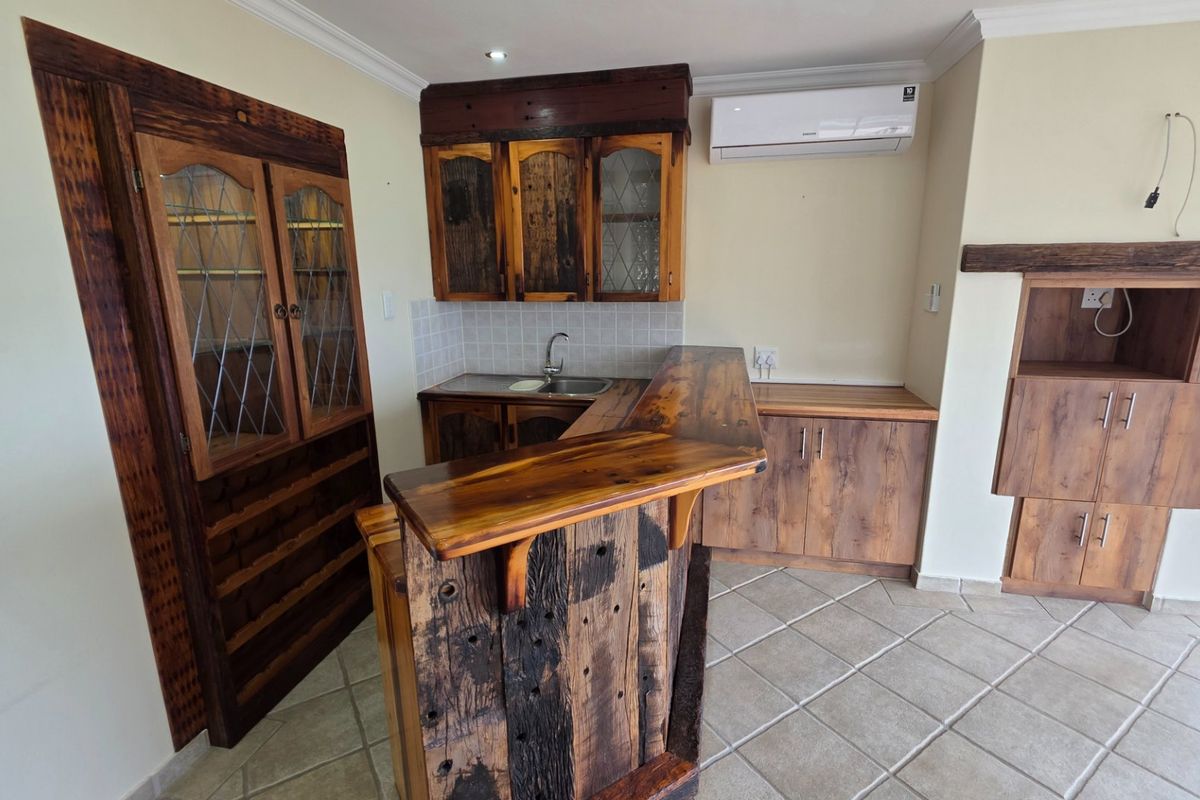 A rustic-style kitchen featuring custom wooden cabinetry, a breakfast bar, tiled flooring, and a wall-mounted air conditioning unit.