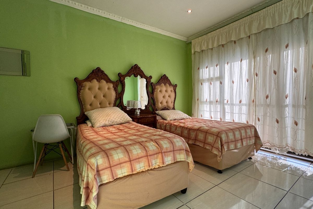 A bedroom featuring tiled flooring, ceiling cornice detailing, and a large sliding glass door providing natural light.