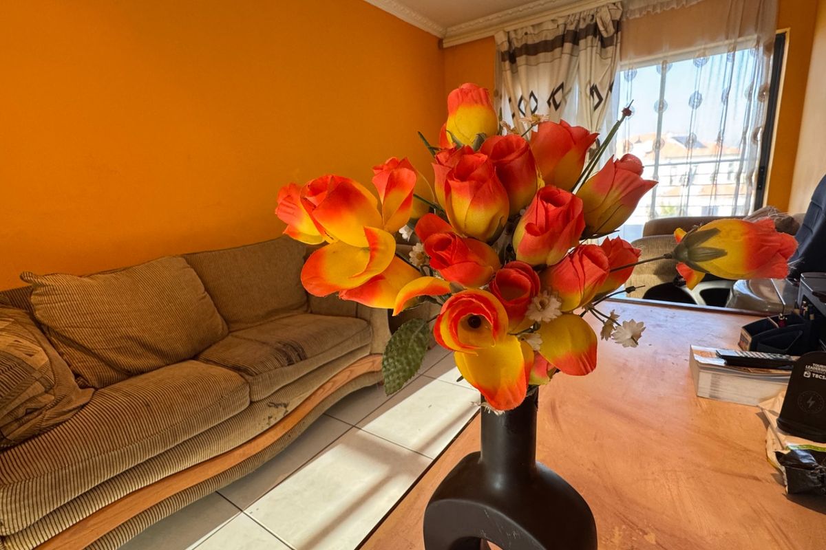 A living room area featuring tiled flooring and decorative ceiling cornicing, currently presented with bright orange wall paint.