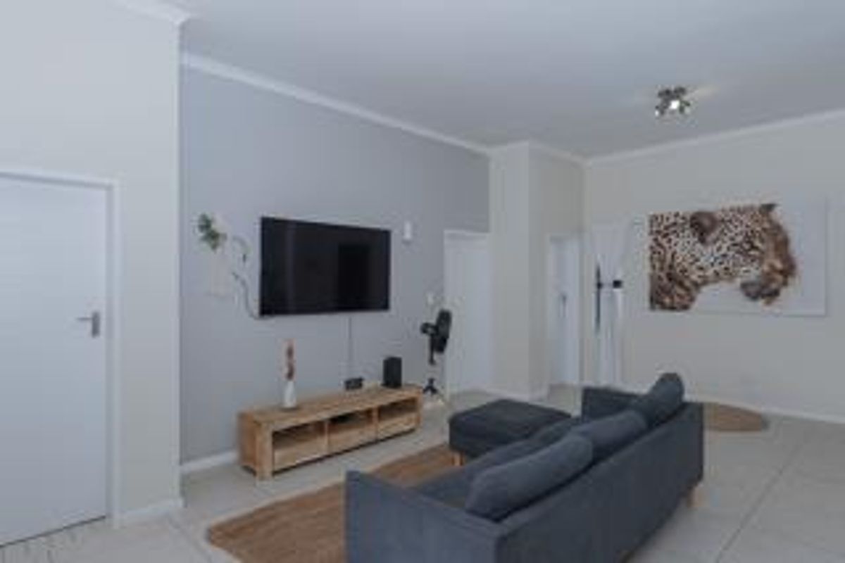 A well-maintained living room featuring neutral wall tones, tiled flooring, and decorative cornice detailing, providing a clean and functional space.