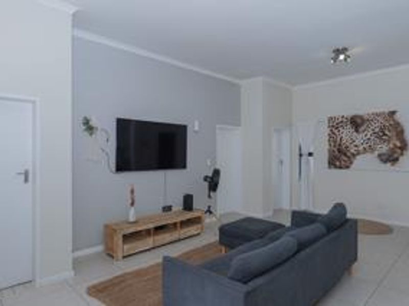 A well-maintained living room featuring neutral wall tones, tiled flooring, and decorative cornice detailing, providing a clean and functional space.
