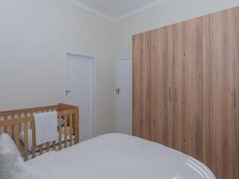 A well-maintained bedroom featuring modern wood-finish built-in cupboards and neutral wall finishes.