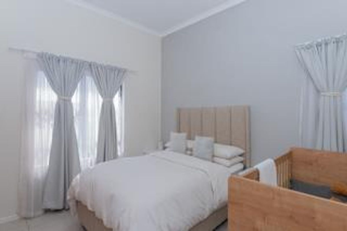 A well-maintained bedroom featuring neutral wall tones, coving, and dual window treatments, providing a bright and comfortable living space.