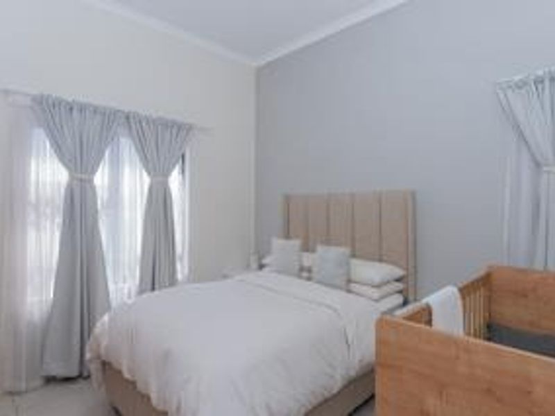A well-maintained bedroom featuring neutral wall tones, coving, and dual window treatments, providing a bright and comfortable living space.