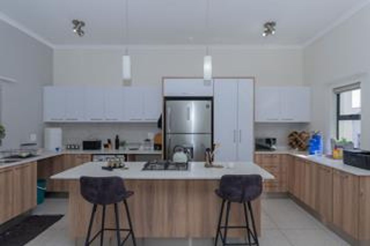 Modern kitchen featuring a central island with a gas hob, stone countertops, ample built-in cabinetry, and stainless steel appliances.