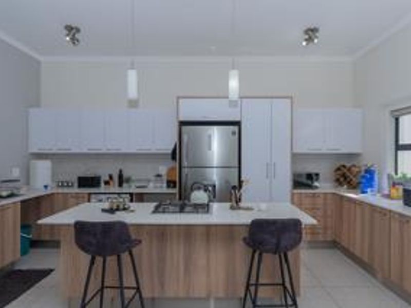 Modern kitchen featuring a central island with a gas hob, stone countertops, ample built-in cabinetry, and stainless steel appliances.