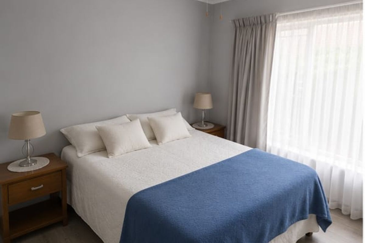 A well-maintained bedroom featuring neutral grey walls, laminate flooring, and a ceiling fan, offering a clean and comfortable living space.