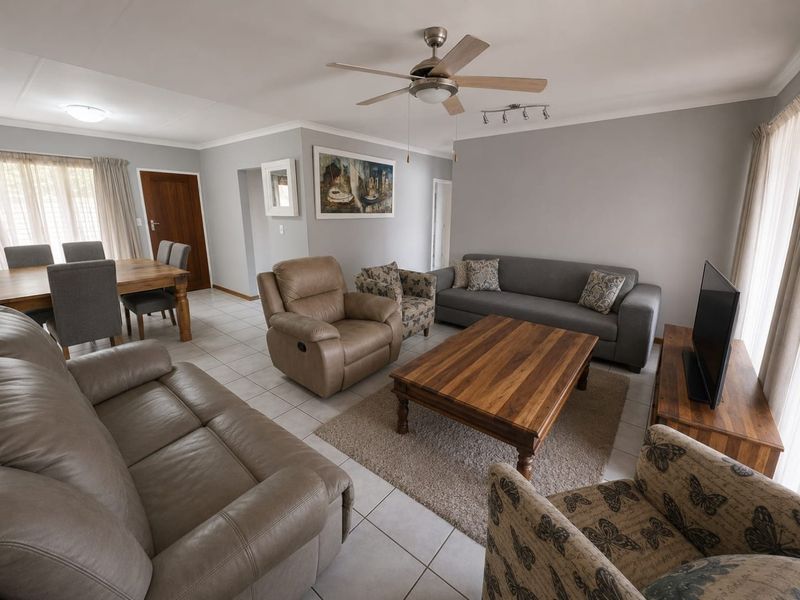 Spacious open-plan living and dining area featuring neutral wall tones, tiled flooring, and a central ceiling fan.