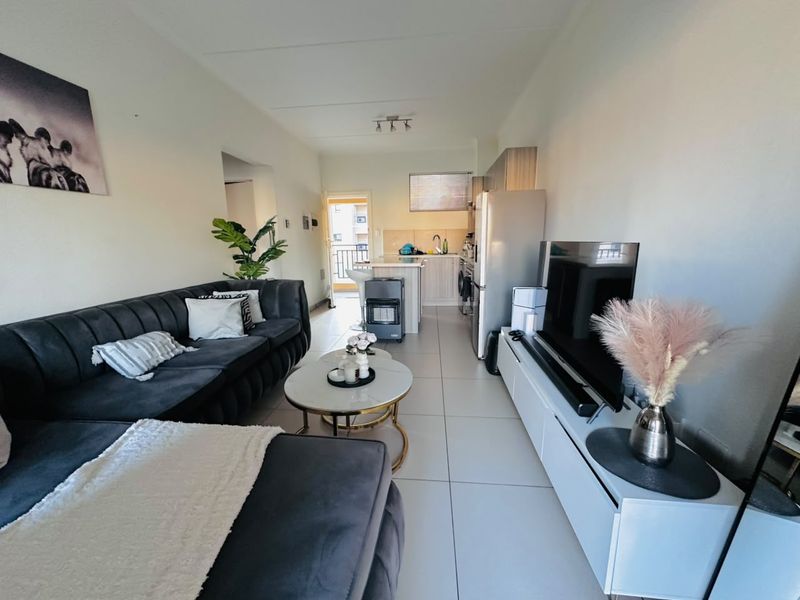 An open-plan living and kitchen area featuring tiled flooring, modern cabinetry, and direct access to a balcony.
