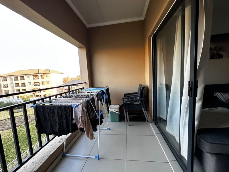 A covered balcony featuring tiled flooring and a metal balustrade, providing an outdoor extension to the living space.