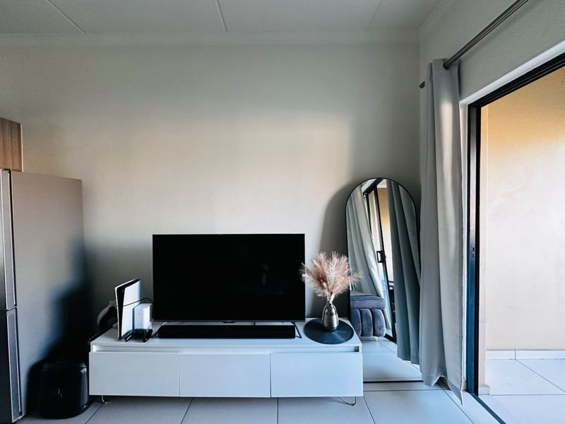 A bright living area featuring tiled flooring and a large sliding glass door providing access to an outdoor space.