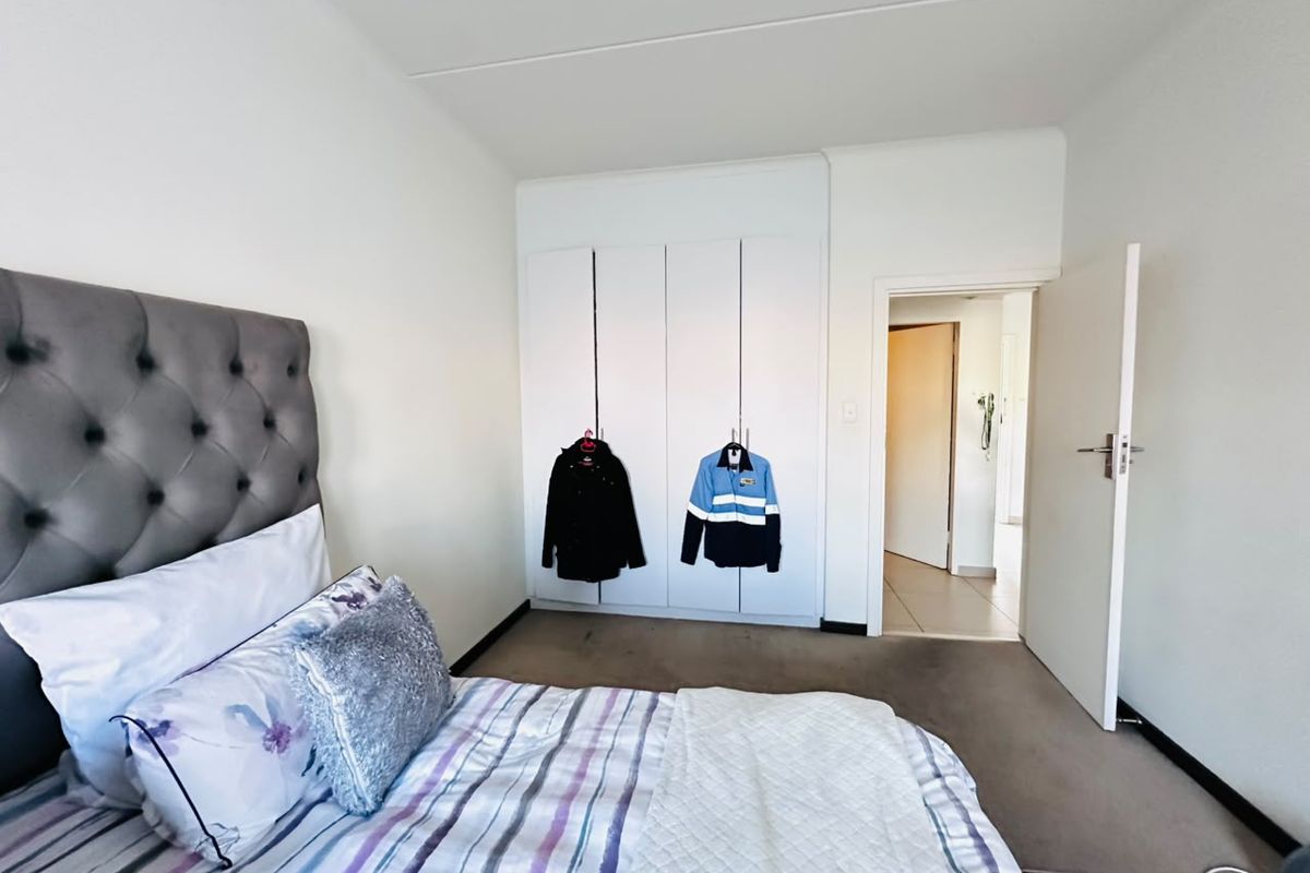 A bedroom featuring built-in cupboards and neutral wall finishes, providing a functional space with direct access to the hallway.