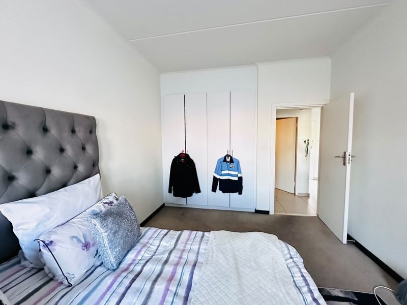A bedroom featuring built-in cupboards and neutral wall finishes, providing a functional space with direct access to the hallway.