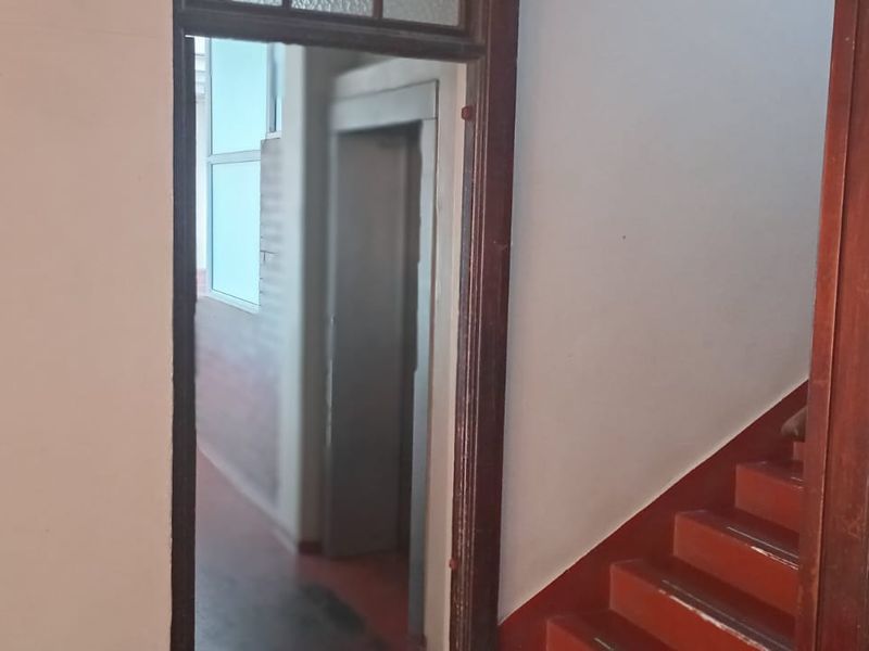 A communal hallway area featuring a staircase and elevator access, showing signs of wear and dated finishes.