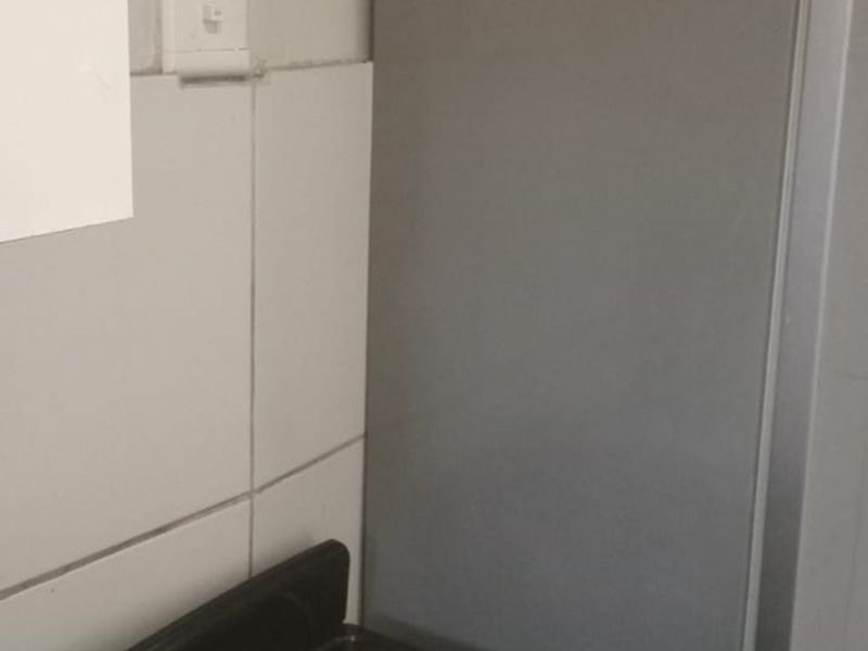 A compact kitchen area featuring a freestanding electric stove and tiled splashback wall finishes.