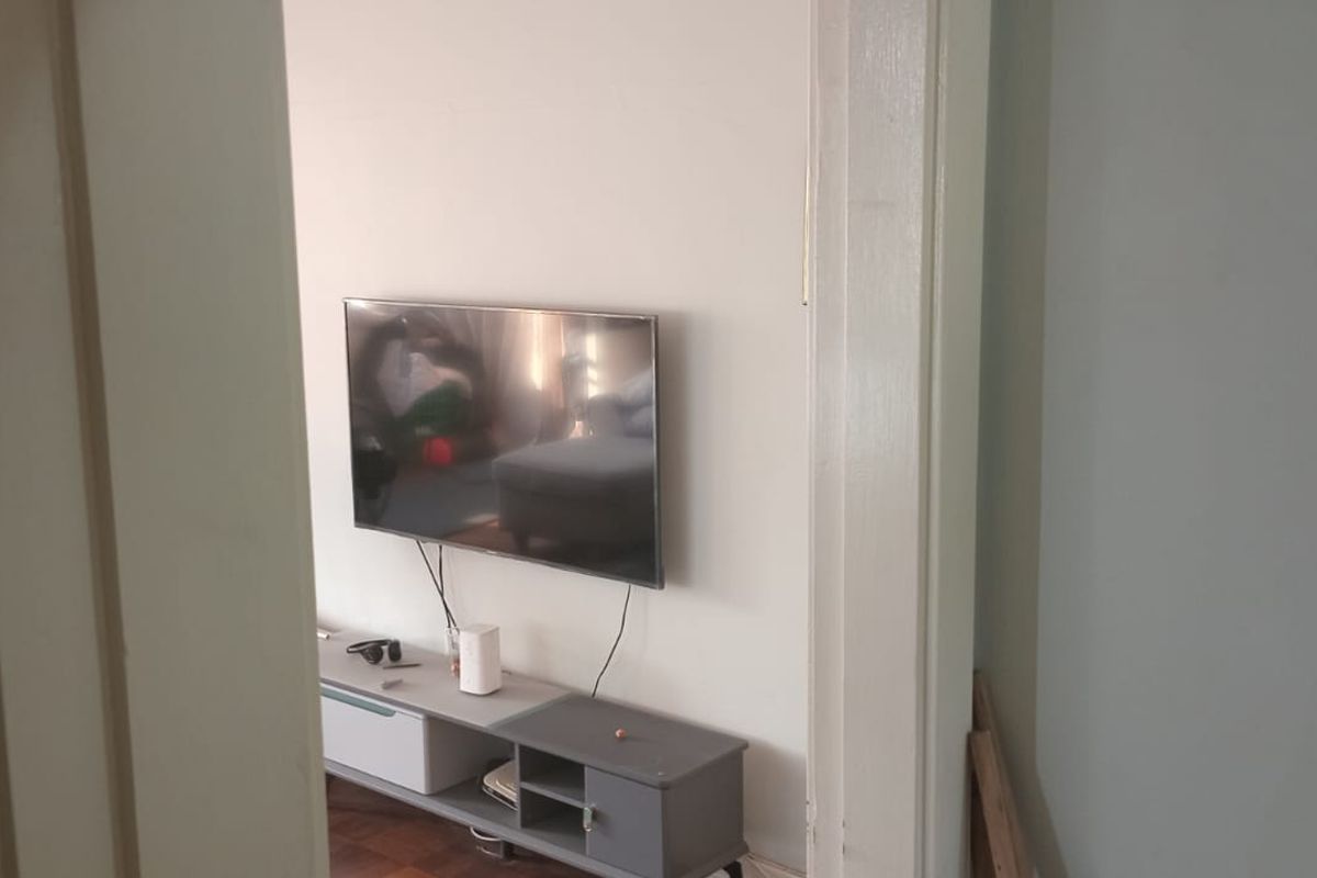 A view into a living room area featuring parquet flooring and a wall-mounted television.