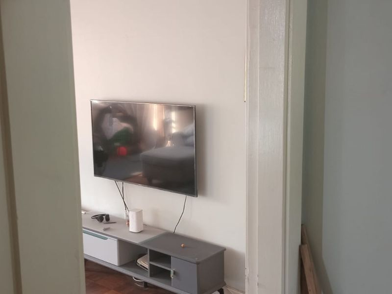 A view into a living room area featuring parquet flooring and a wall-mounted television.