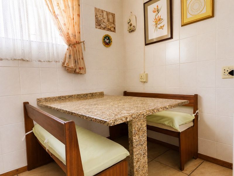 A compact kitchen breakfast nook featuring a built-in granite-topped table and tiled wall finishes.