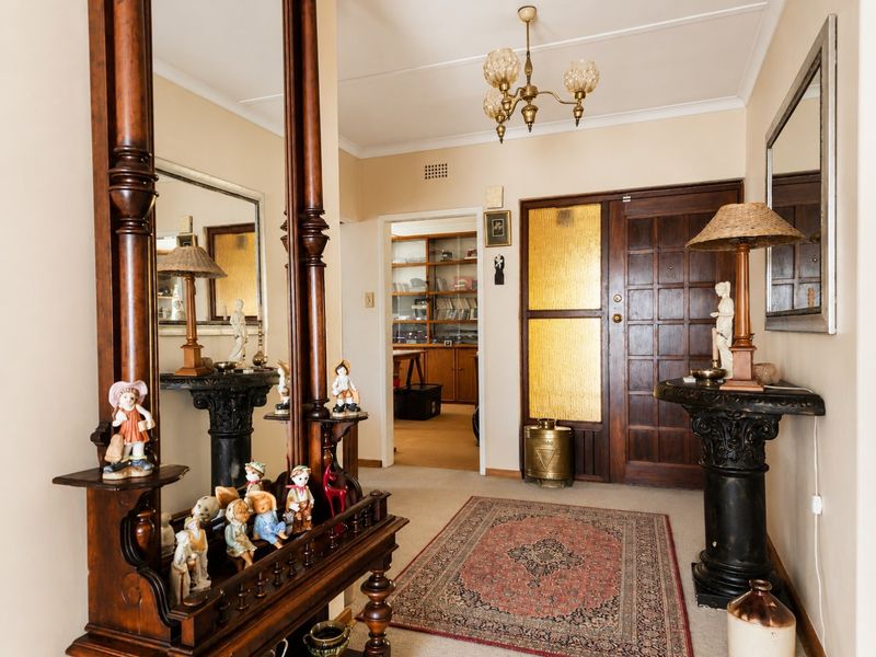 Welcoming entrance hall featuring a classic timber front door with textured glass panels and a traditional chandelier.