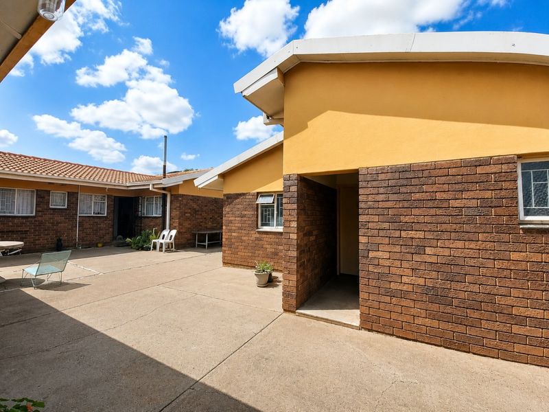 A spacious rear courtyard featuring face brick walls, concrete paving, and access to the main dwelling structure.