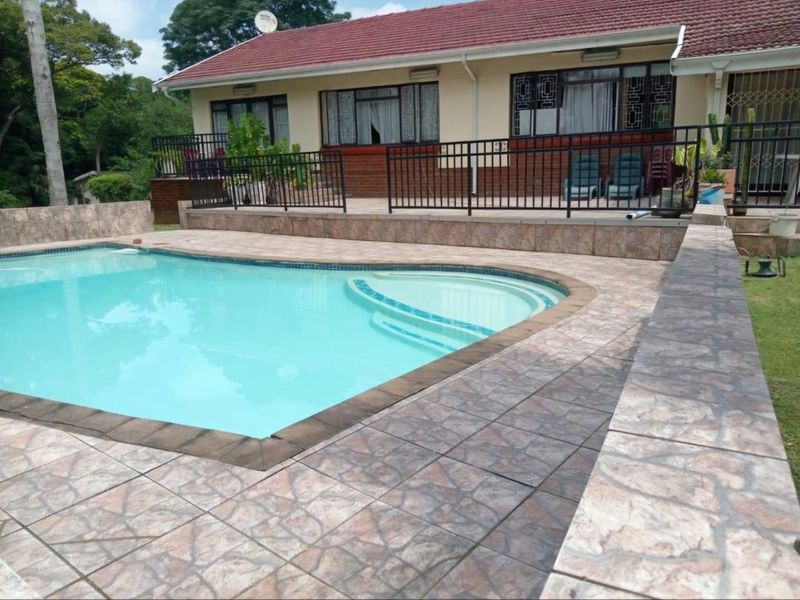 Outdoor pool area featuring a tiled deck, metal safety railing, and direct access to the rear patio of the house.