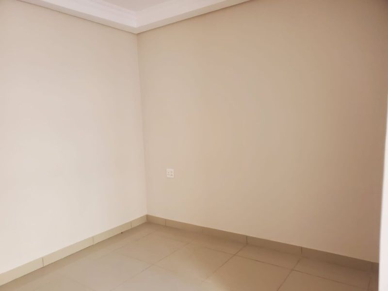 A clean, empty interior space featuring neutral wall paint, tiled flooring, and simple cove cornice detailing.