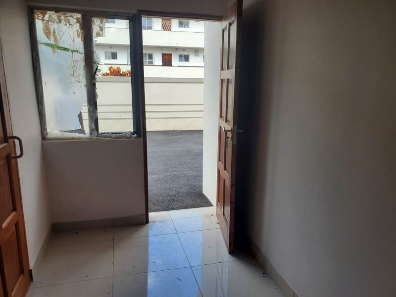 An empty entry area featuring tiled flooring and a timber door, with visible damage to the window glazing requiring repair.