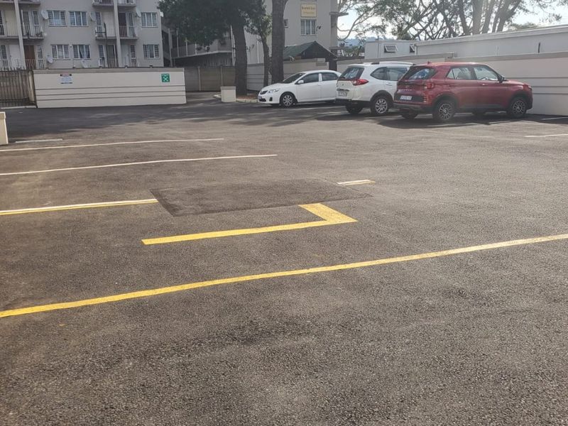 Commercial parking area featuring asphalt surfacing, marked parking bays, and perimeter boundary walls.