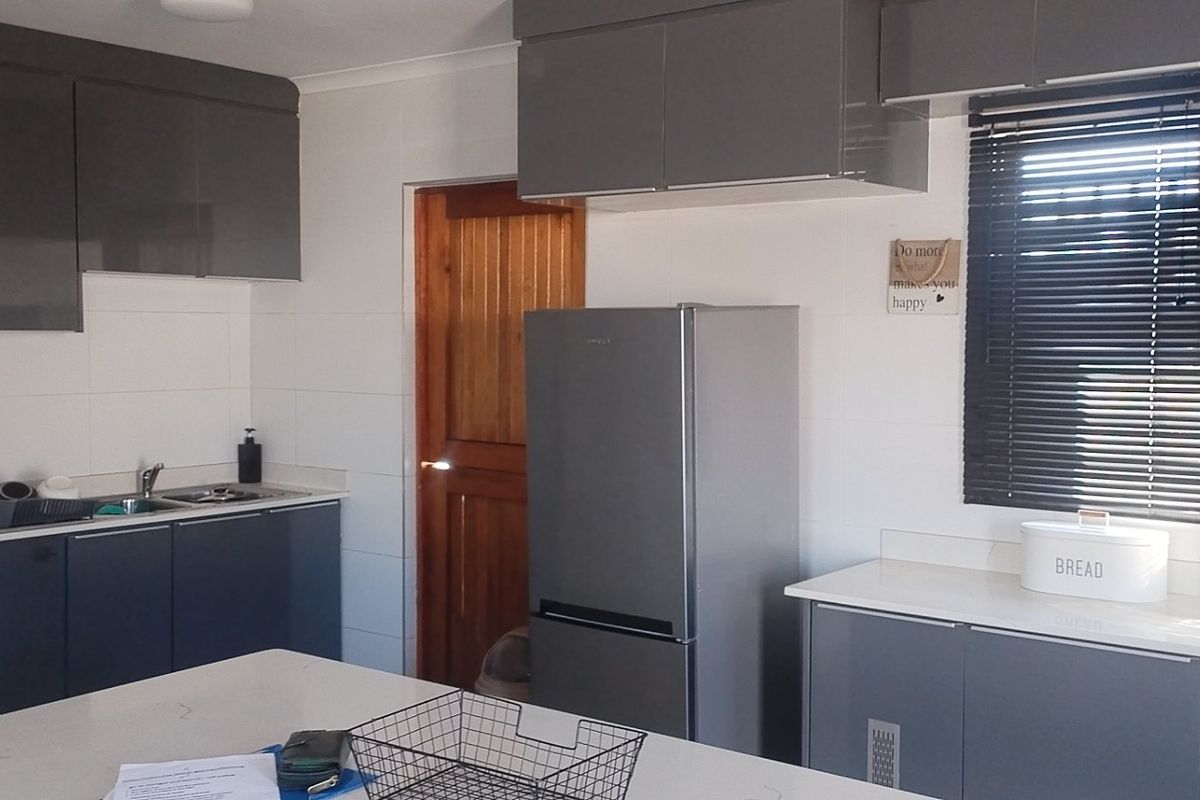 Modern kitchen featuring sleek grey cabinetry, stone countertops, tiled splashbacks, and a functional layout with ample storage space.