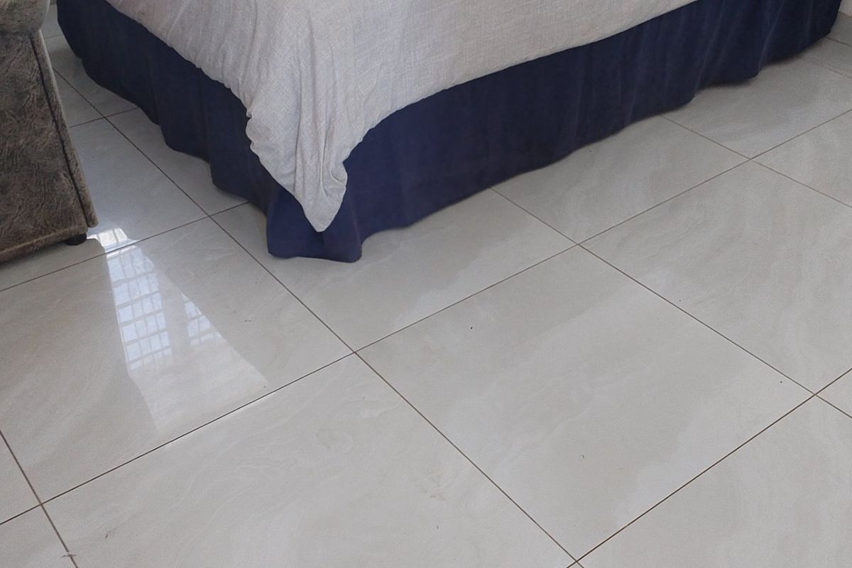 A bedroom interior featuring clean, light-colored porcelain floor tiles.