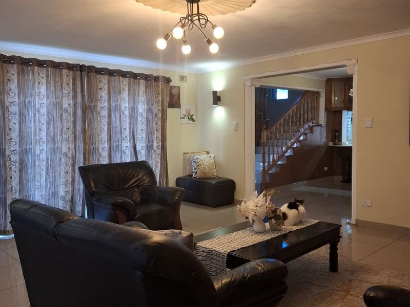 A spacious living room featuring tiled flooring, a decorative ceiling rose, and an open transition to the staircase area.