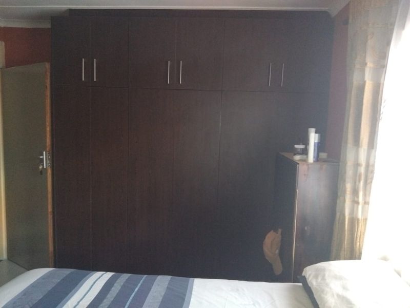 A bedroom featuring dark wood built-in cupboards providing ample storage space.