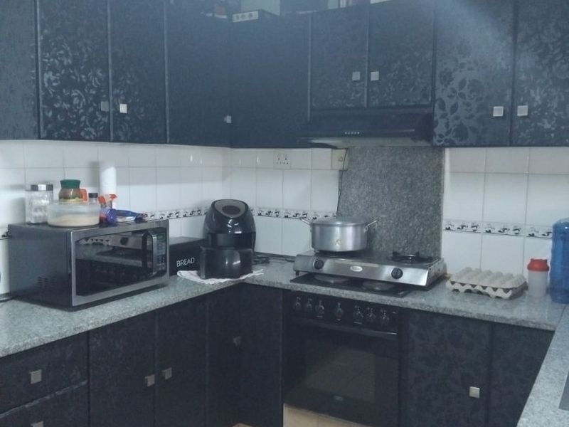 A functional kitchen featuring dark patterned cabinetry, granite countertops, a gas hob with extractor fan, and tiled flooring.