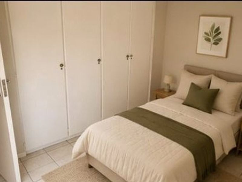 A cozy bedroom featuring built-in cupboards and neutral tiled flooring, offering a clean and functional living space.