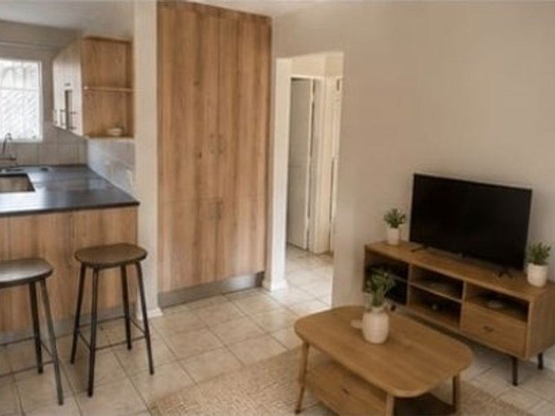 Open plan living area featuring a compact kitchen with built-in cabinetry, tiled flooring, and a functional layout connecting to the living space.
