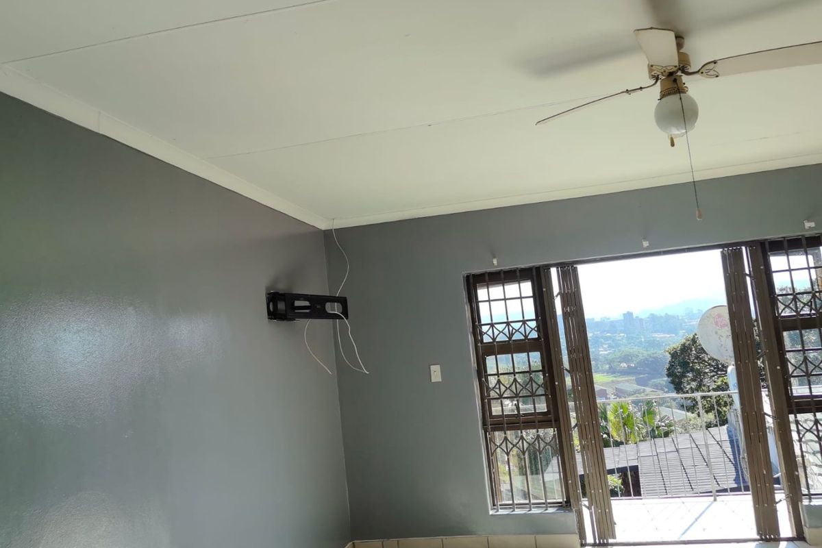 Living room featuring tiled flooring, a ceiling fan, and a sliding door leading to a balcony with scenic views.