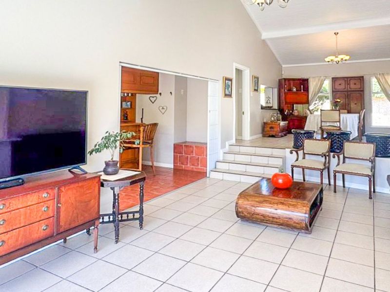 Spacious open-plan living area featuring tiled floors, a vaulted ceiling, and a split-level layout connecting to a secondary kitchen or dining space.