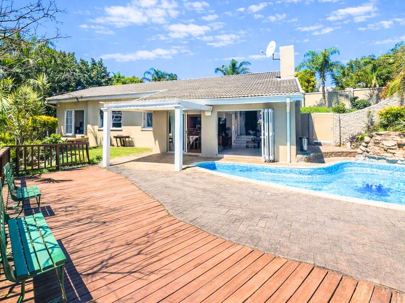 Rear exterior view featuring a swimming pool, timber deck, paved patio area with a pergola, and direct access to the home via bi-fold doors.