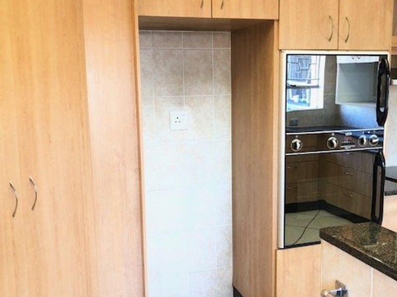 A functional kitchen area featuring light wood-finish cabinetry, a built-in oven, tiled splashback, and granite countertops.