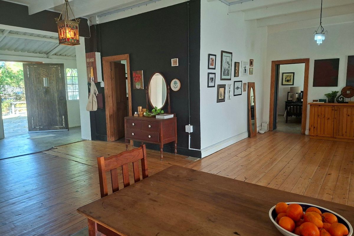 Spacious living area featuring exposed timber ceiling beams, polished hardwood flooring, and characterful solid timber doors connecting to adjacent rooms.