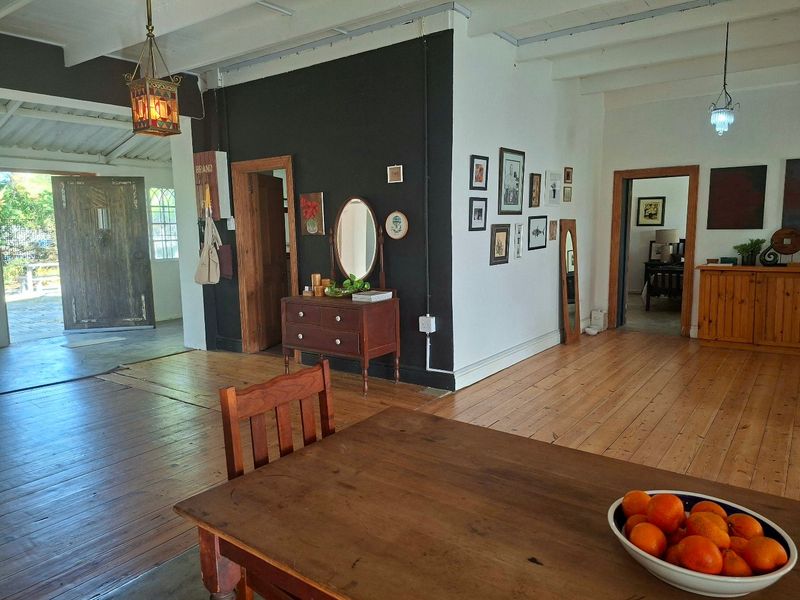 Spacious living area featuring exposed timber ceiling beams, polished hardwood flooring, and characterful solid timber doors connecting to adjacent rooms.
