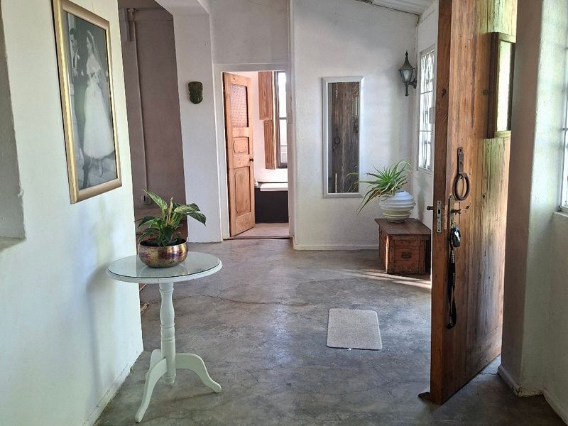 Entrance foyer featuring exposed beam ceilings, concrete flooring, and a solid timber front door leading into the home.