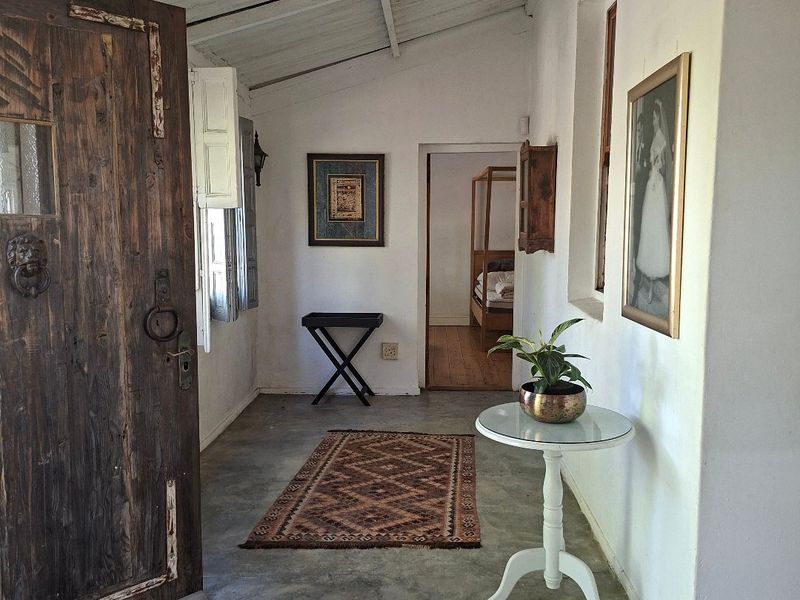 Entrance hall featuring rustic timber door, exposed beam ceiling, and polished concrete flooring, leading into the main living areas of the home.