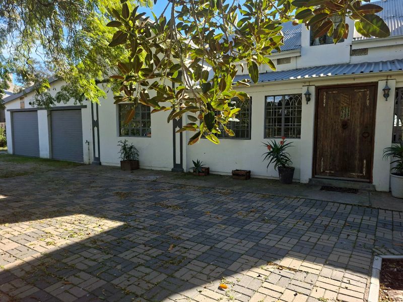 Front elevation of a residence featuring a paved driveway, double garage, and a distinctive timber entrance door with leaded glass window detailing.