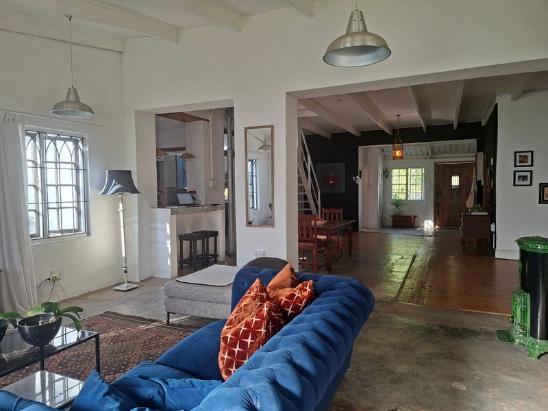 Spacious open-plan living area featuring exposed beam ceilings, concrete floors, and a characterful wood-burning stove, creating a warm and inviting atmosphere.